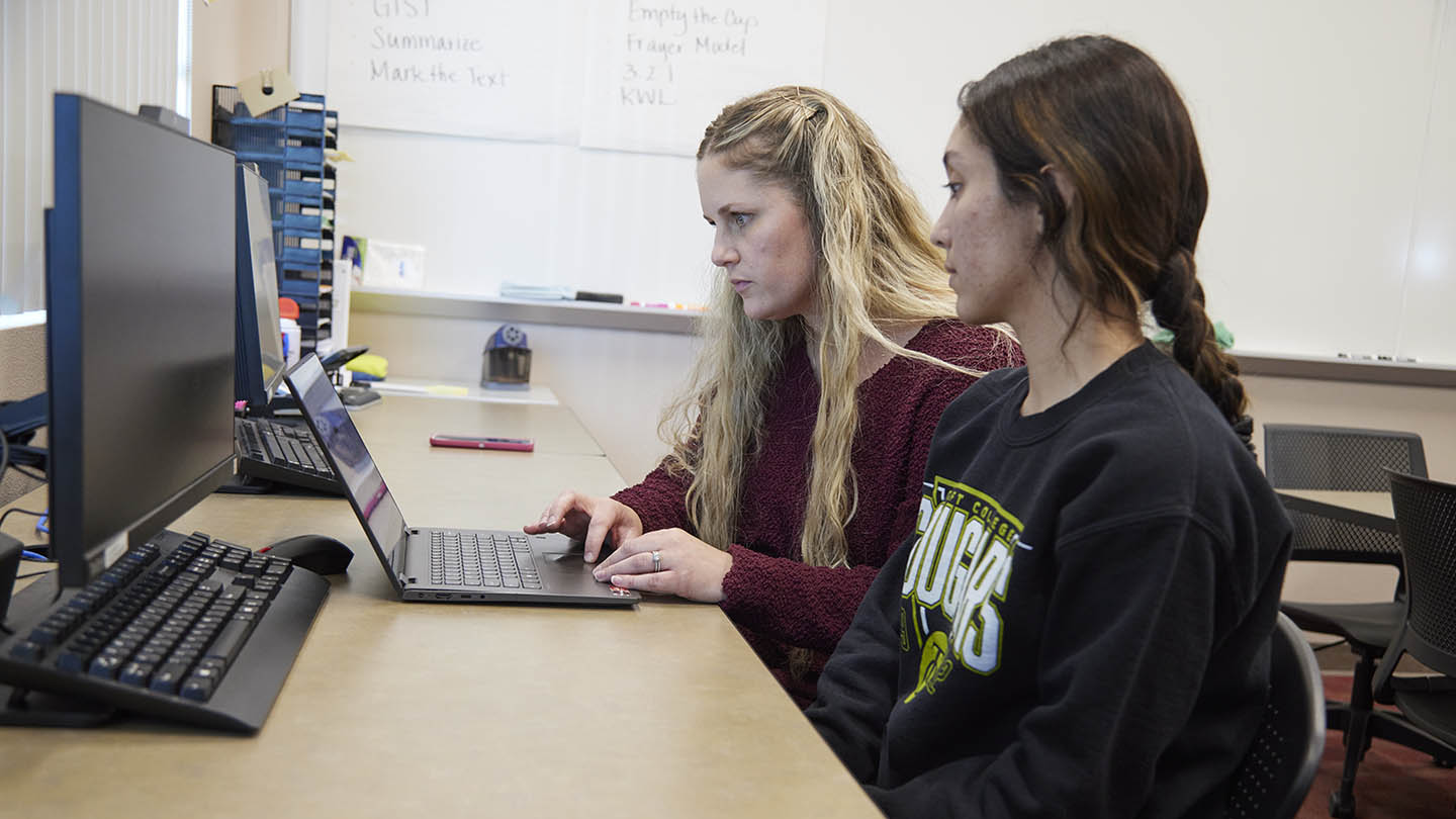 A female professor discusses a writing assignment with one of her female students.