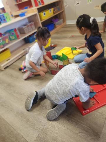 three children play on the floor with toys