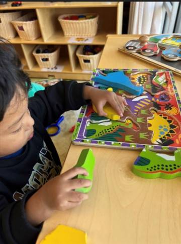 child working on puzzle at table