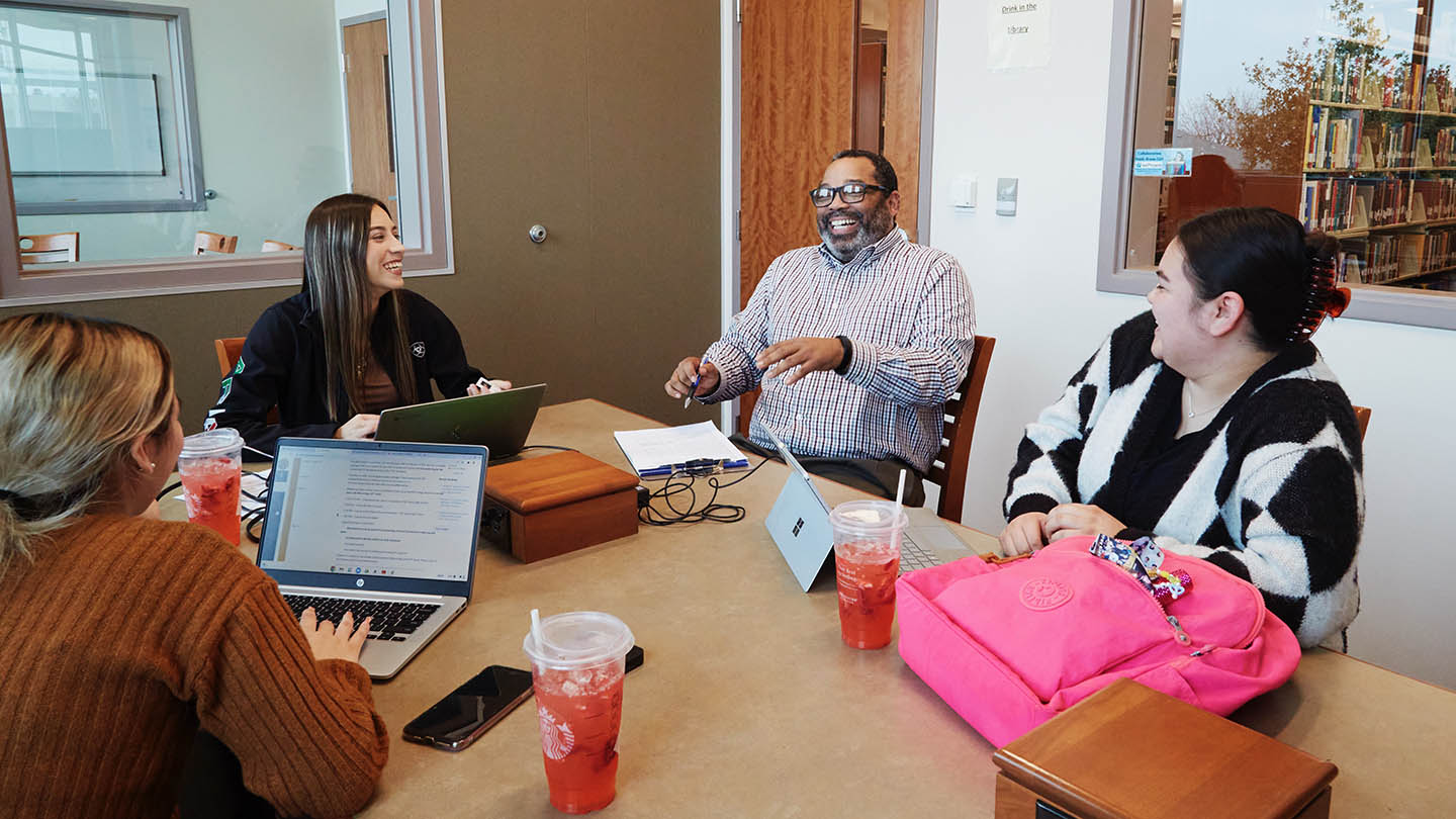 Male student services leader shares a laugh with three female students.