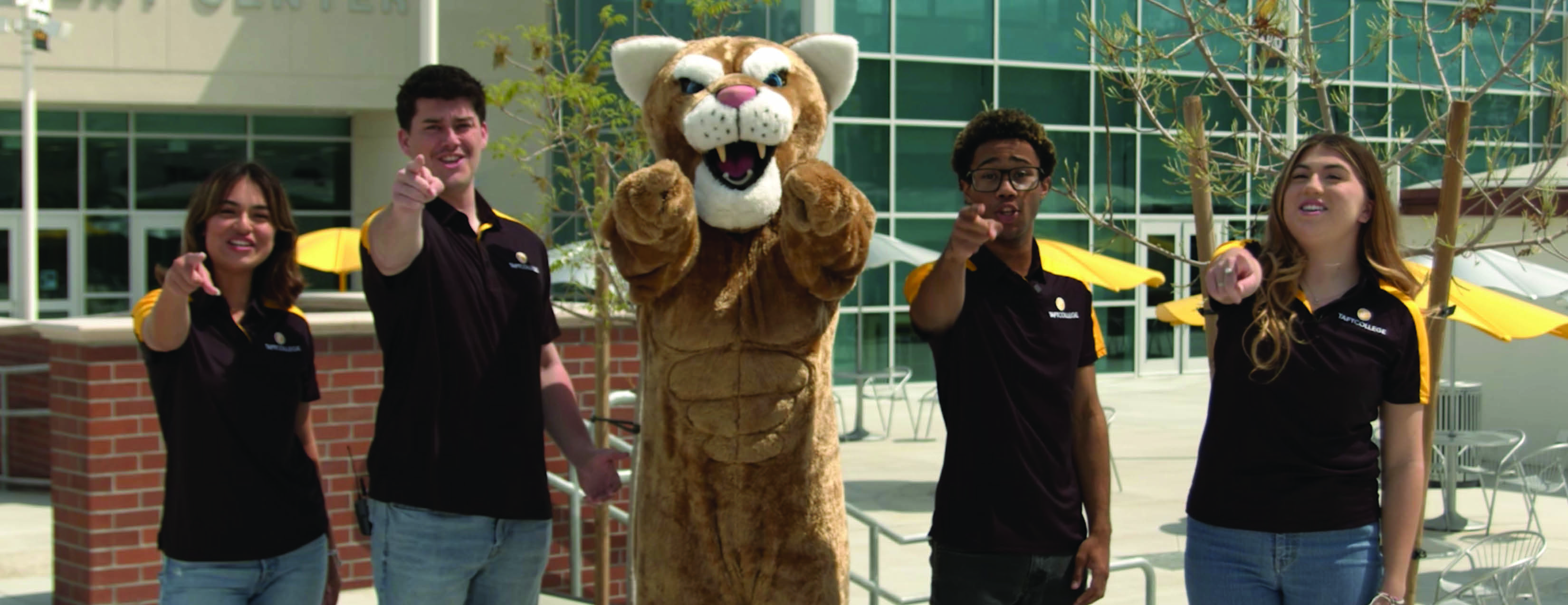 Four students welcome visitors to the quad.